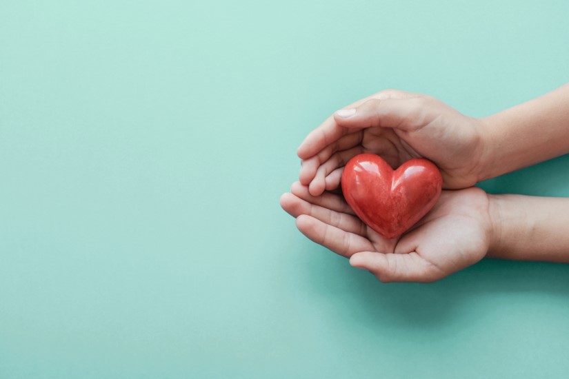 Outstretched hands holding a simple, red heart