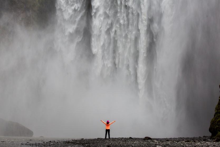 Person standing underneath a waterfall