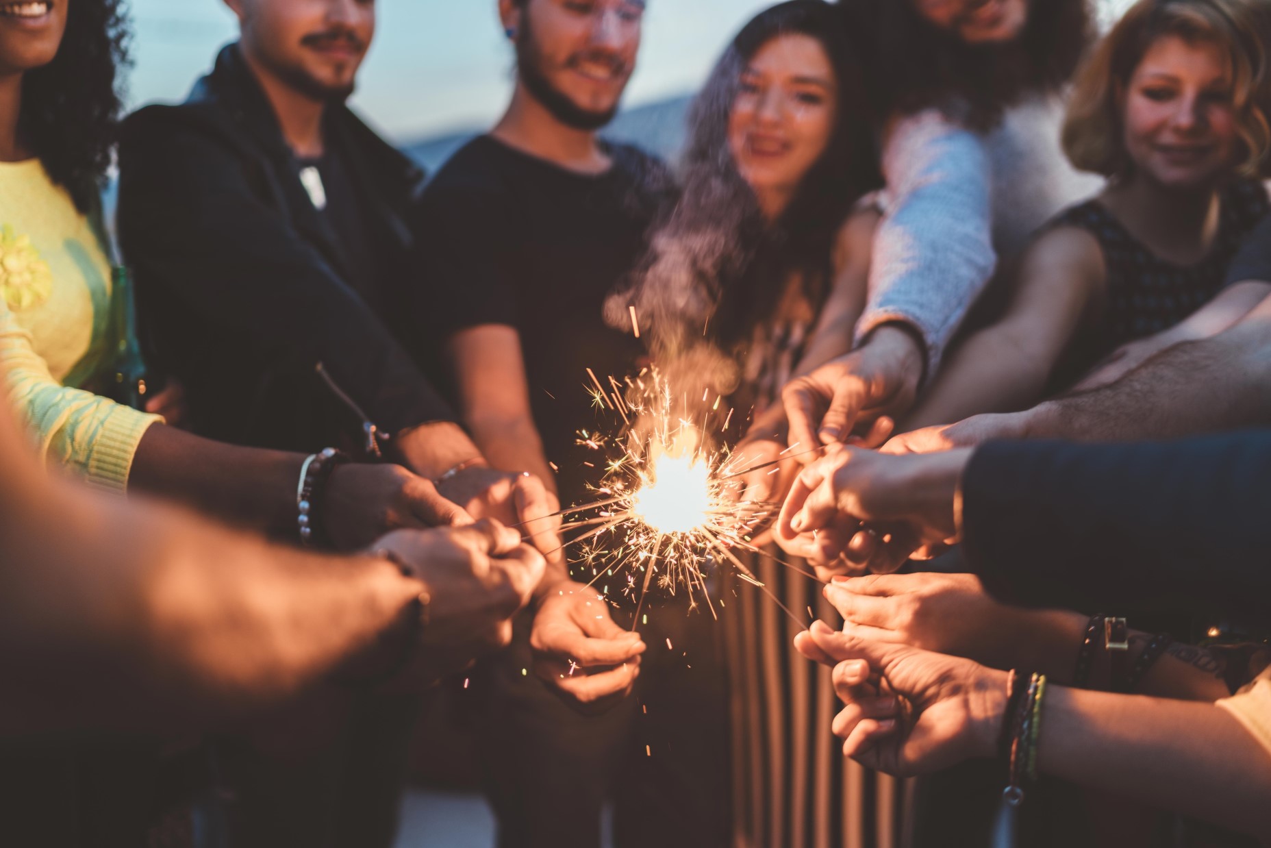 Folks holding sparklers together in a circle