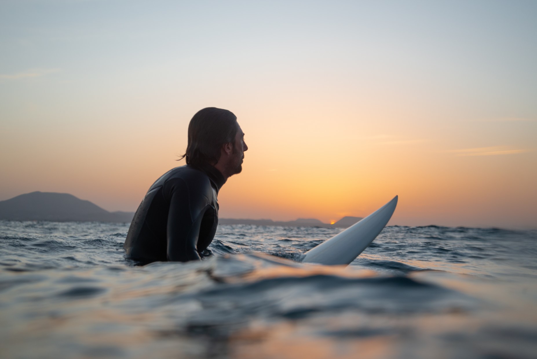 Man sitting on surf board contemplating