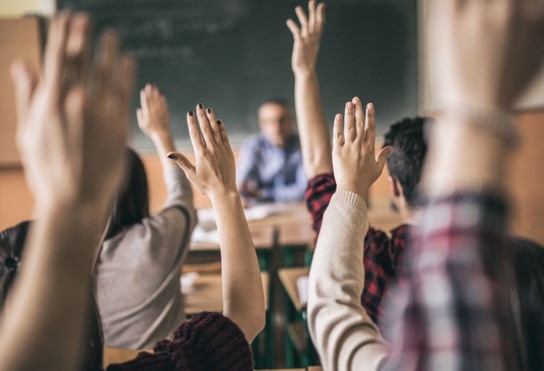 Many hands raised in a classroom setting