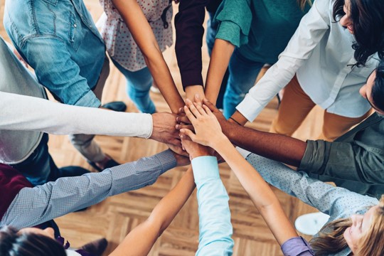 Hands of the team members touching as if to say Go Team!